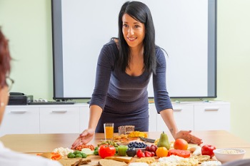 Eine Ernährungsberaterin unterrichtet Auszubildende über die Inhaltsstoffe von Obst- und Gemüse