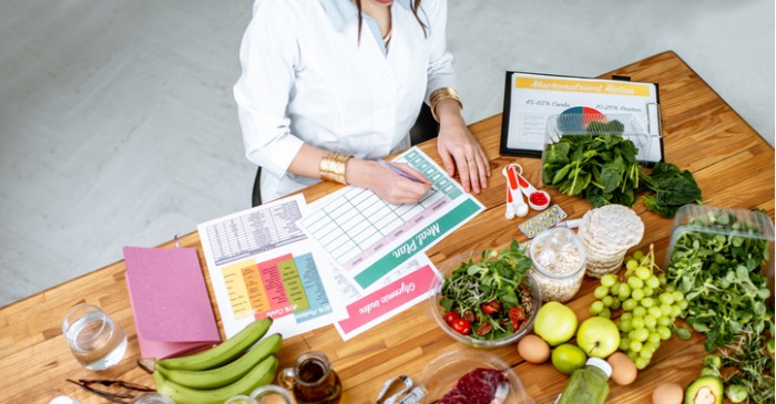 Ernährungsberaterin sitzt am Schreibtisch und wertet Ernährungspläne von Klienten aus